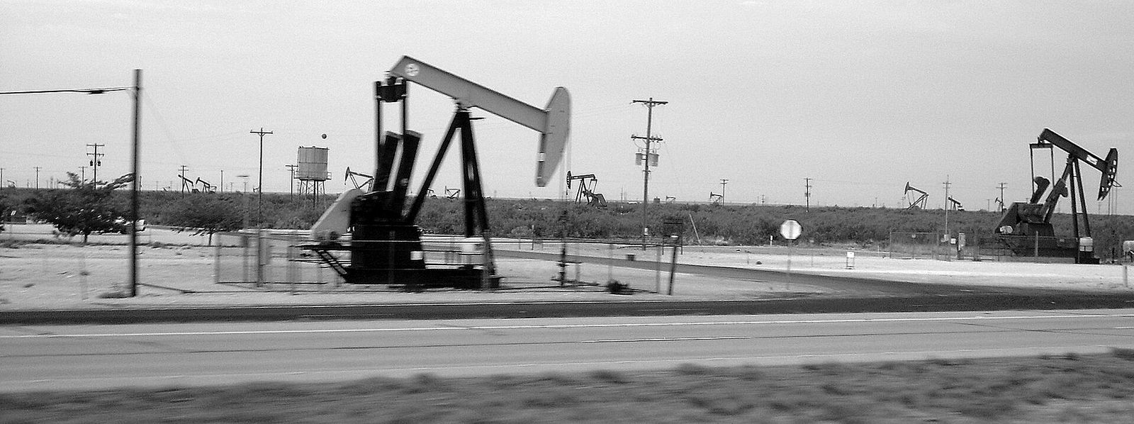 A line of oil pumpjacks beside a highway in West Texas